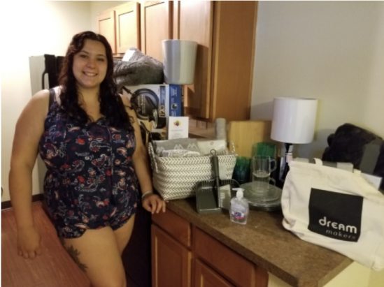 Smiling young lady in her first apartment with a kit of necessities